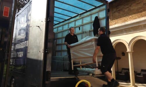 Two movers loading a van with large furniture
